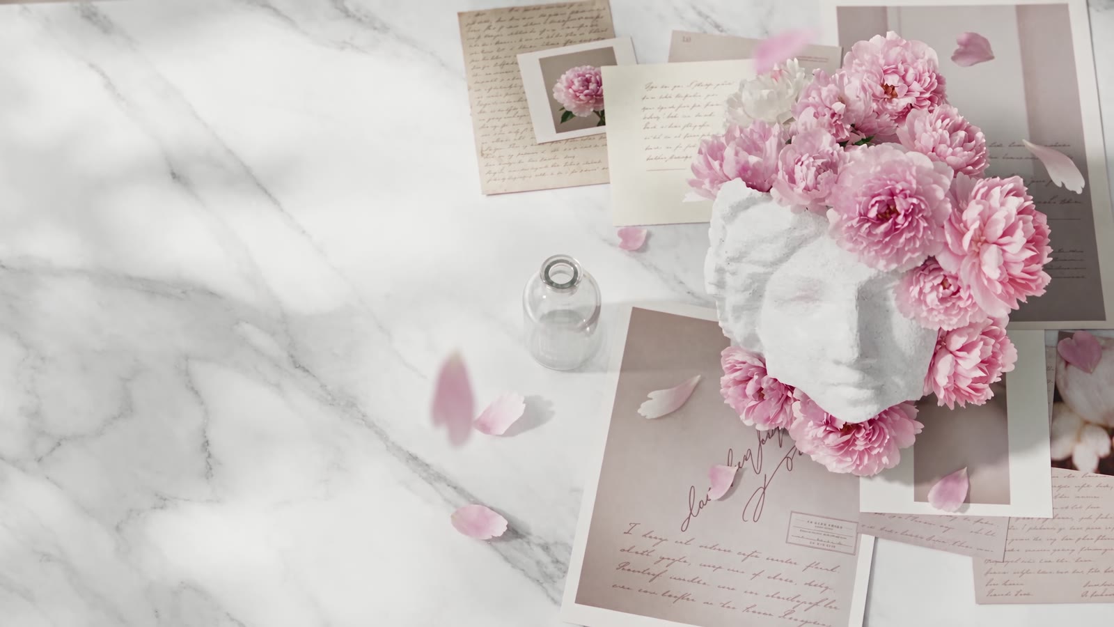 Un piano di marmo con peonie rosa, cartoline e appunti a mano che compongono un moodboard